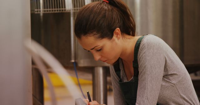 Woman in Work Uniform Taking Notes in Industrial Setting - Download Free Stock Images Pikwizard.com