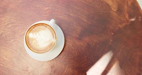 Latte Art Cappuccino in White Ceramic Cup on Wooden Table