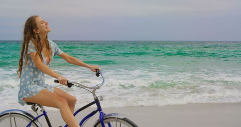 Joyful Woman Biking Along Sunlit Beach Shoreline - Download Free Stock Images Pikwizard.com