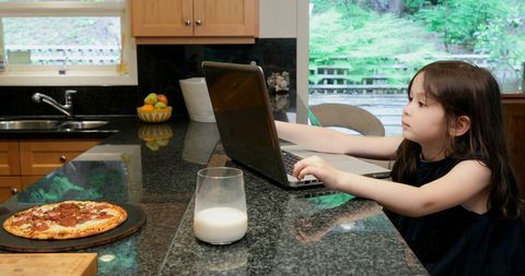 Young Girl Engaged with Laptop in Modern Kitchen