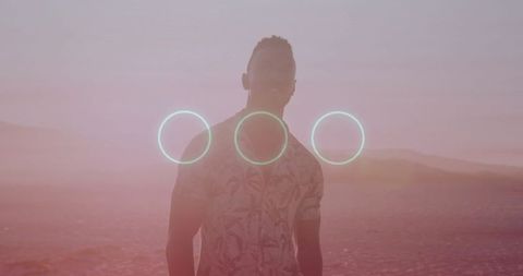 Man gazing across desert with mystical glowing rings in twilight