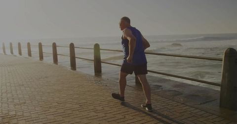 Senior Man Jogging by Seaside Promenade in Morning Light
