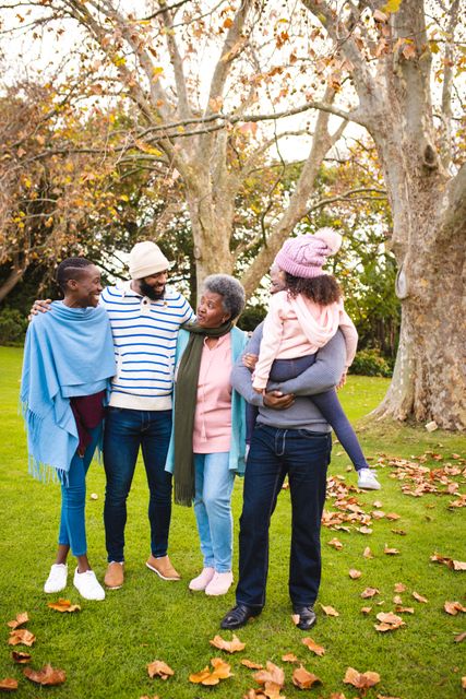 Happy african american multi-generation family standing on grassy land in park during winter. Unaltered, togetherness, love, childhood, lifestyle and nature concept.