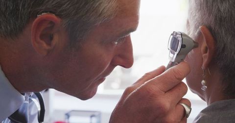Doctor Examining Ears with Otoscope in Medical Checkup