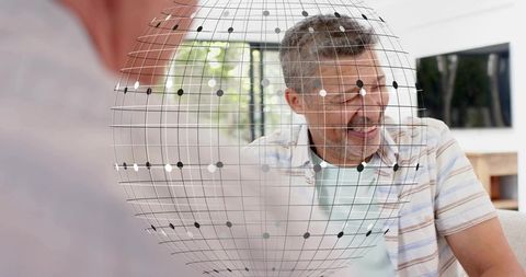 Smiling middle-aged man leaning forward chatting in living room with digital globe overlay