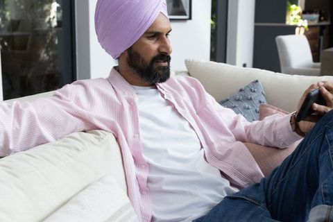Turbaned Man Relaxing with Smartphone on Sofa