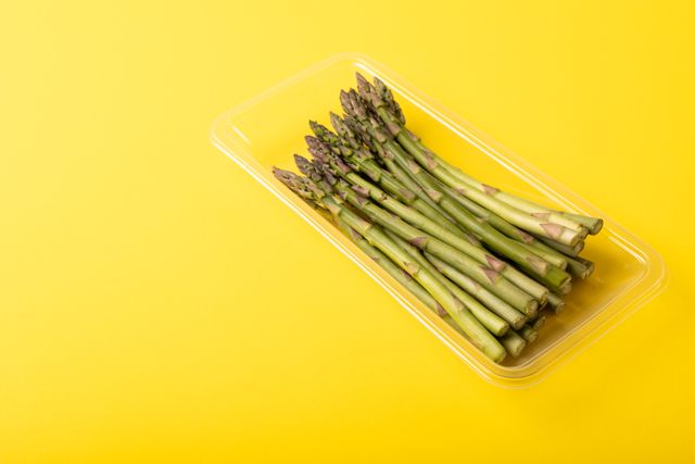 High angle view of asparagus in container on yellow background, copy space. unaltered, food, healthy eating, studio shot and organic.