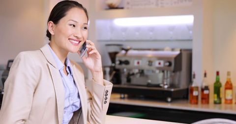 Smiling businesswoman talking on phone at bar counter