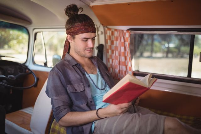 Young man reading book in mini van