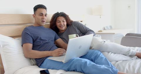 Happy Gay Couple Relaxing with Coffee and Laptop on Bed - Download Free Stock Images Pikwizard.com
