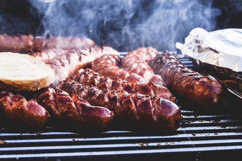 Sausages sizzling on charcoal grill with toasted bread and smoky summer barbecue