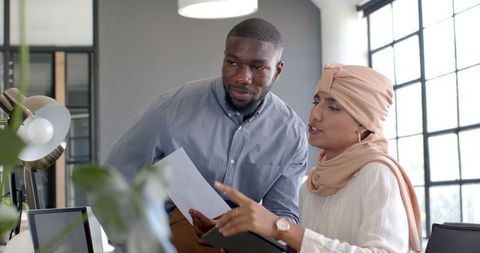 Diverse team discussing office project with documents and technology