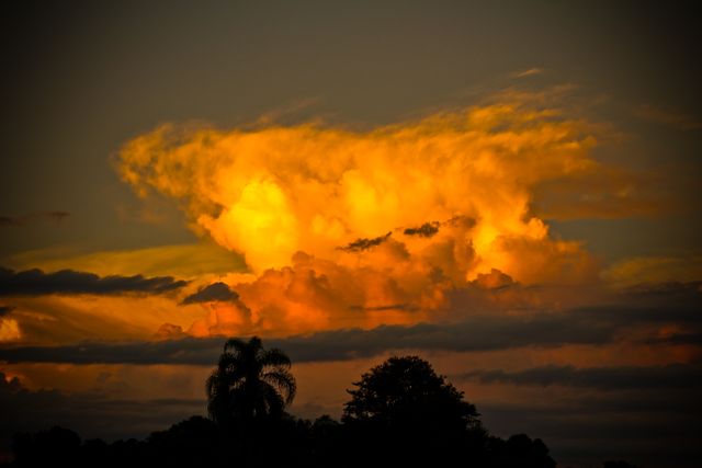 Glowing orange clouds contrast against a darkening evening sky, providing a dramatic and picturesque nature scene. Ideal for use in nature blogs, weather articles, travel promotions, or evening serenity-related digital content.