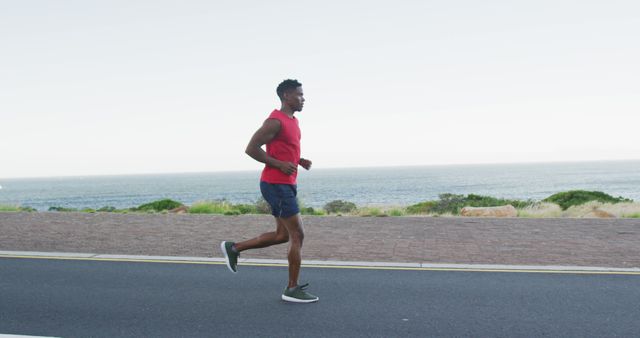African american man exercising outdoors running on a coastal road. fitness training and healthy outdoor lifestyle.