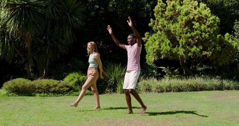 Diverse Friends Walking Barefoot on Lush Green Lawn in Sunshine
