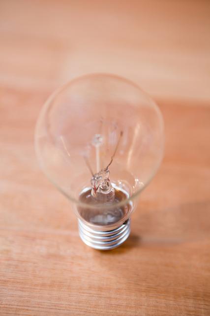 Image features an electric bulb placed on a wooden surface. Ideal for concepts related to energy, electricity, home improvement, interior design, minimalism, and innovative ideas. Suitable for both print and digital uses.