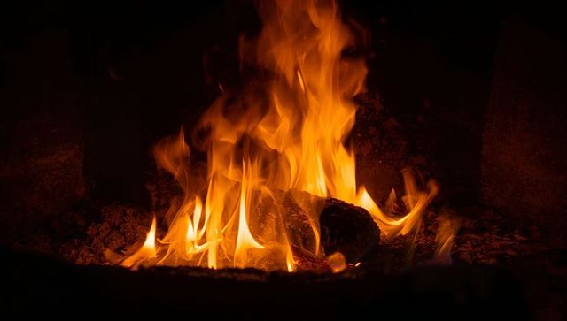 Crackling Flames Warming Charred Log with Glowing Embers in Hearth