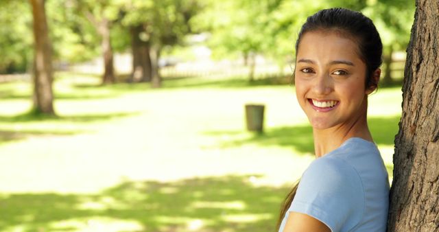 Happy Young Woman Relaxing Outdoors Leaning on Tree - Download Free Stock Images Pikwizard.com