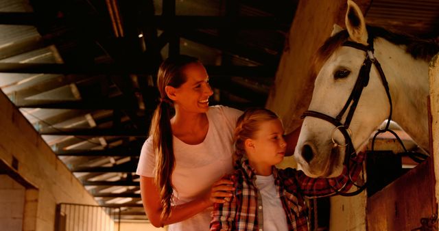 A Caucasian woman and a girl enjoy a bonding moment with a horse in a stable, with copy space - Download Free Stock Photos Pikwizard.com