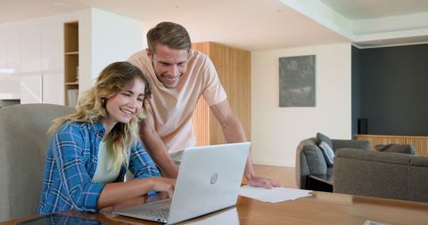 Happy couple collaborating on laptop at home