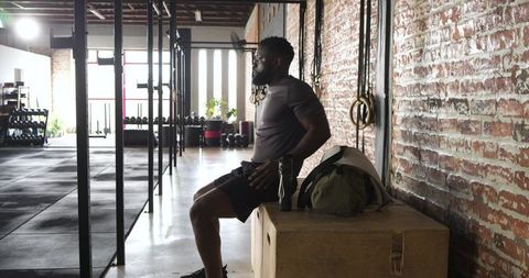 Man sitting in industrial gym contemplating workout