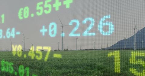 Wind turbines powering green energy markets with digital stock ticker overlay