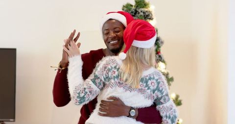 Joyful couple dancing beside christmas tree in festive attire