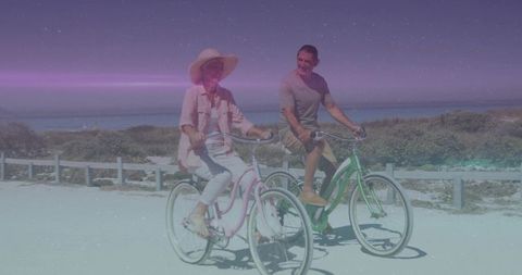 Couple cycling on pastel bicycles along coastal path