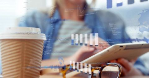 Woman tapping tablet at cafe, reviewing analytics dashboards with coffee and glasses