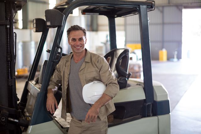 Portrait of happy worker standing near forklift - Download Free Stock Photos Pikwizard.com