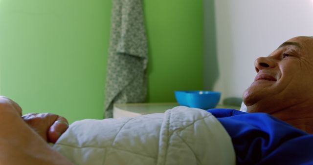 Elderly man lying in hospital bed, smiling and looking hopeful. Ideal for subjects like healthcare, senior care, patient recovery, medical services, and wellbeing.