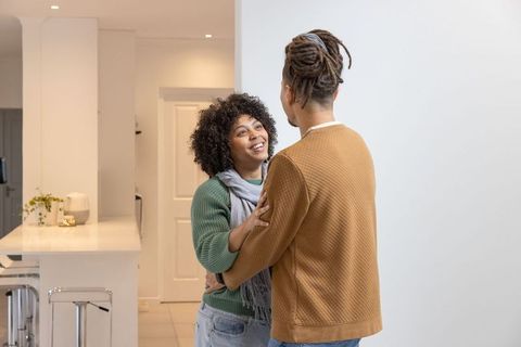 Couple embracing and smiling in contemporary kitchen with floating hearts over island