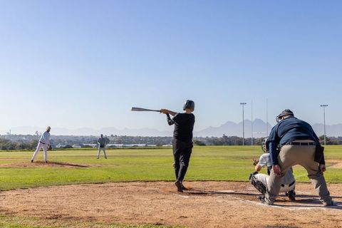 Senior Baseball Players Batting Practice on Sunny Park Field with Pitcher, Catcher, Umpire