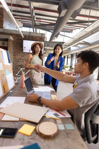 Diverse team collaborating in creative office with laptop and color swatches