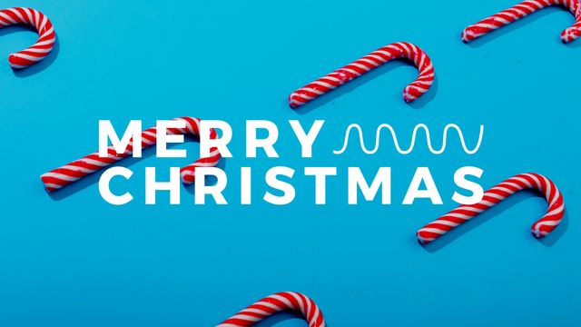 Horizontal image of merry christmas text, with candy canes on blue background. Christmas, seasonal greetings, tradition and celebration concept digitally generated image.
