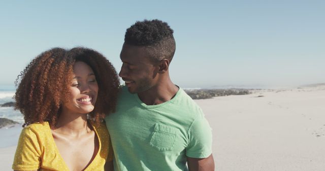 Happy biracial couple standing on beach, hugging and laughing. Summer, relaxation, vacation, happy time, summer time, romance.