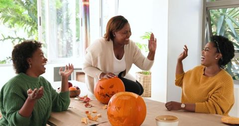 African american women celebrating with joyful pumpkin carving gathering