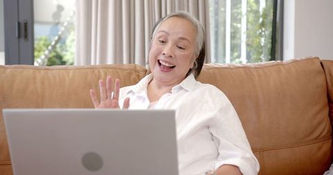 Elderly Woman Video Chatting on Laptop at Home
