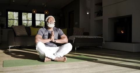 Mature African American Man Practicing Yoga Meditation on Mat at Home