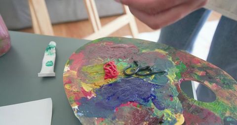 African american artist mixing thick acrylic paints on palette close-up vibrant texture