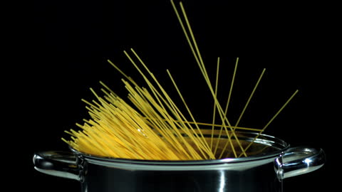 Spaghetti Falling into Pot Against Black Background
