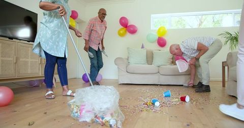 Senior friends tidying up confetti after celebration