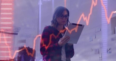 Young professional woman analyzing stock market charts on tablet with data overlay