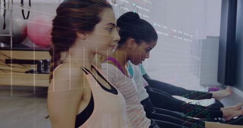 Women performing seated stretches in bright pilates studio with exercise balls and mirror