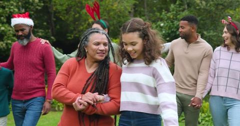 Diverse Multigenerational Family Dancing Outdoors in Festive Sweaters