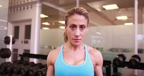 Female athlete training with dumbbells in gym, showcasing strength, focus and discipline