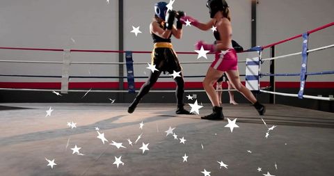 Two female boxers sparring in ring wearing headgear and gloves during intense training