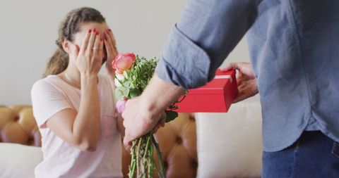Surprised woman receiving flowers and gift box from partner
