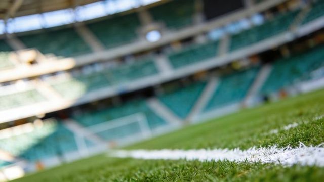 Close-up stadium turf and white sideline leading to blurred goal and empty green seats