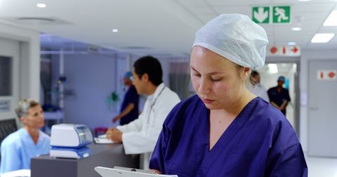 Focused Nurse Writing on Clipboard in Hospital Environment - Download Free Stock Images Pikwizard.com